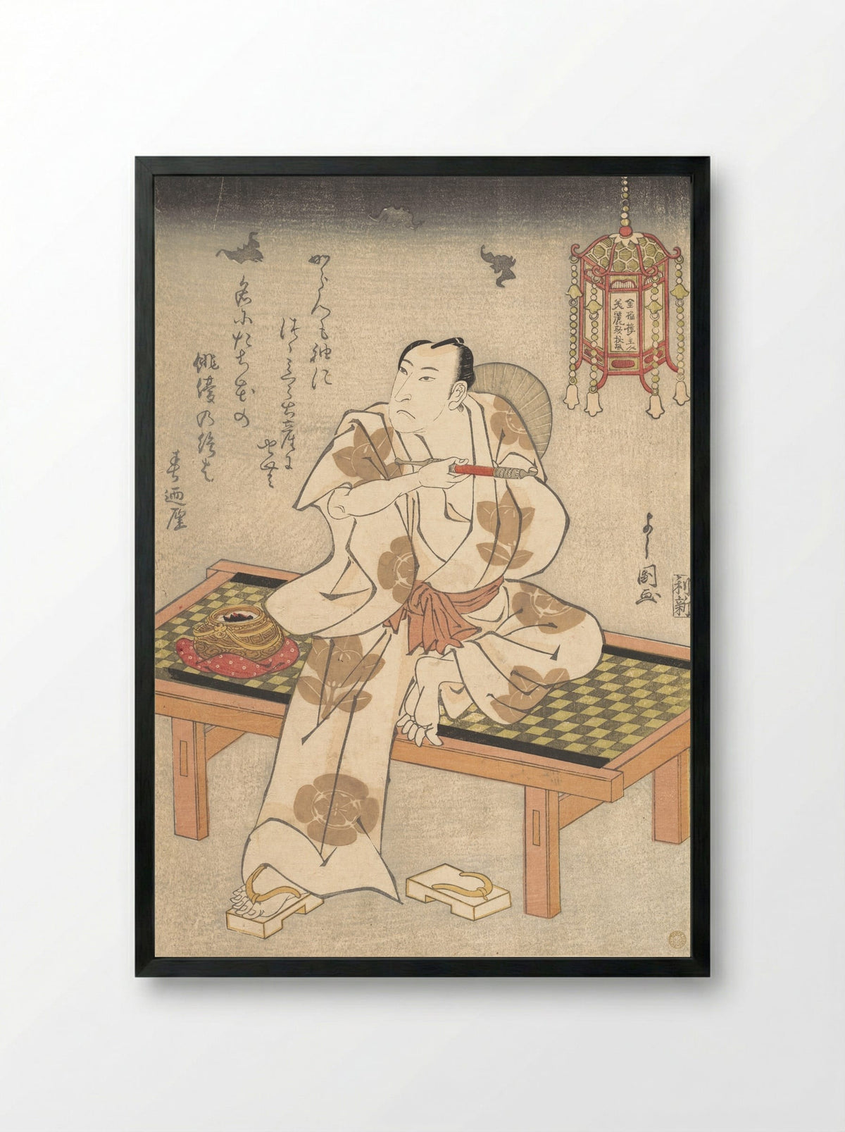 An Actor of the Ichimura Line Sitting on a Shogi (Wooden Bench) and Holding a Pipe - Ippyotei Yoshikuni - Framed Print Black